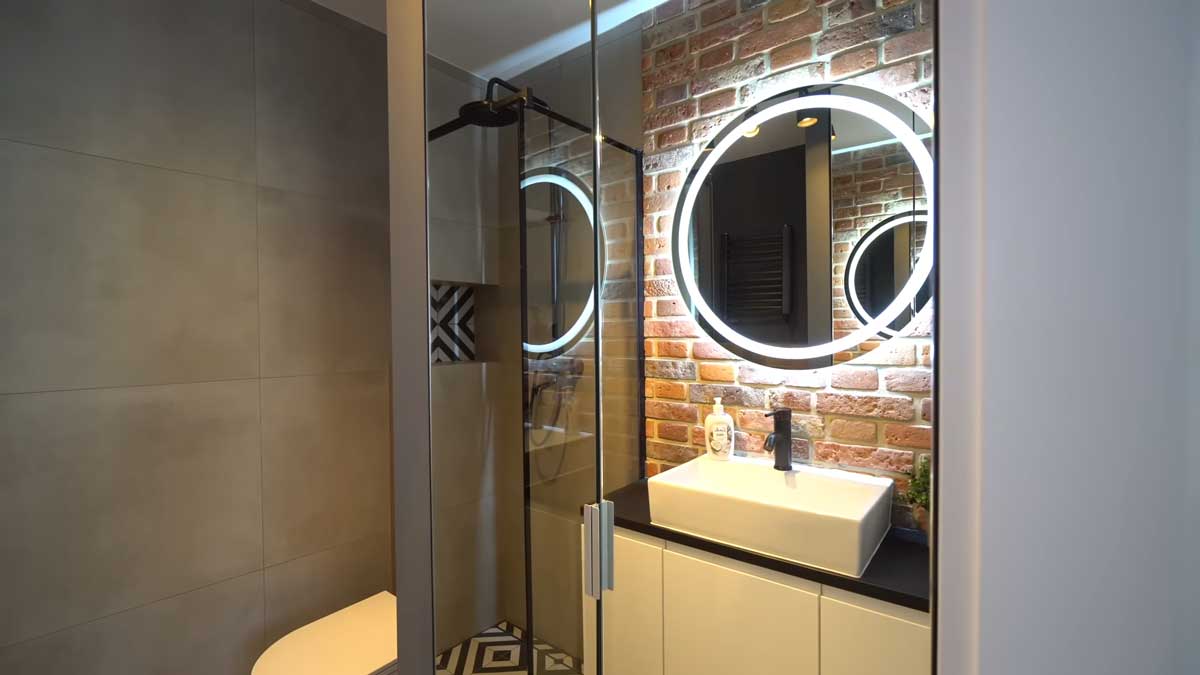 Moderní koupelna s walk-in sprchovým koutem a cihlovým obkladem v malém bytě