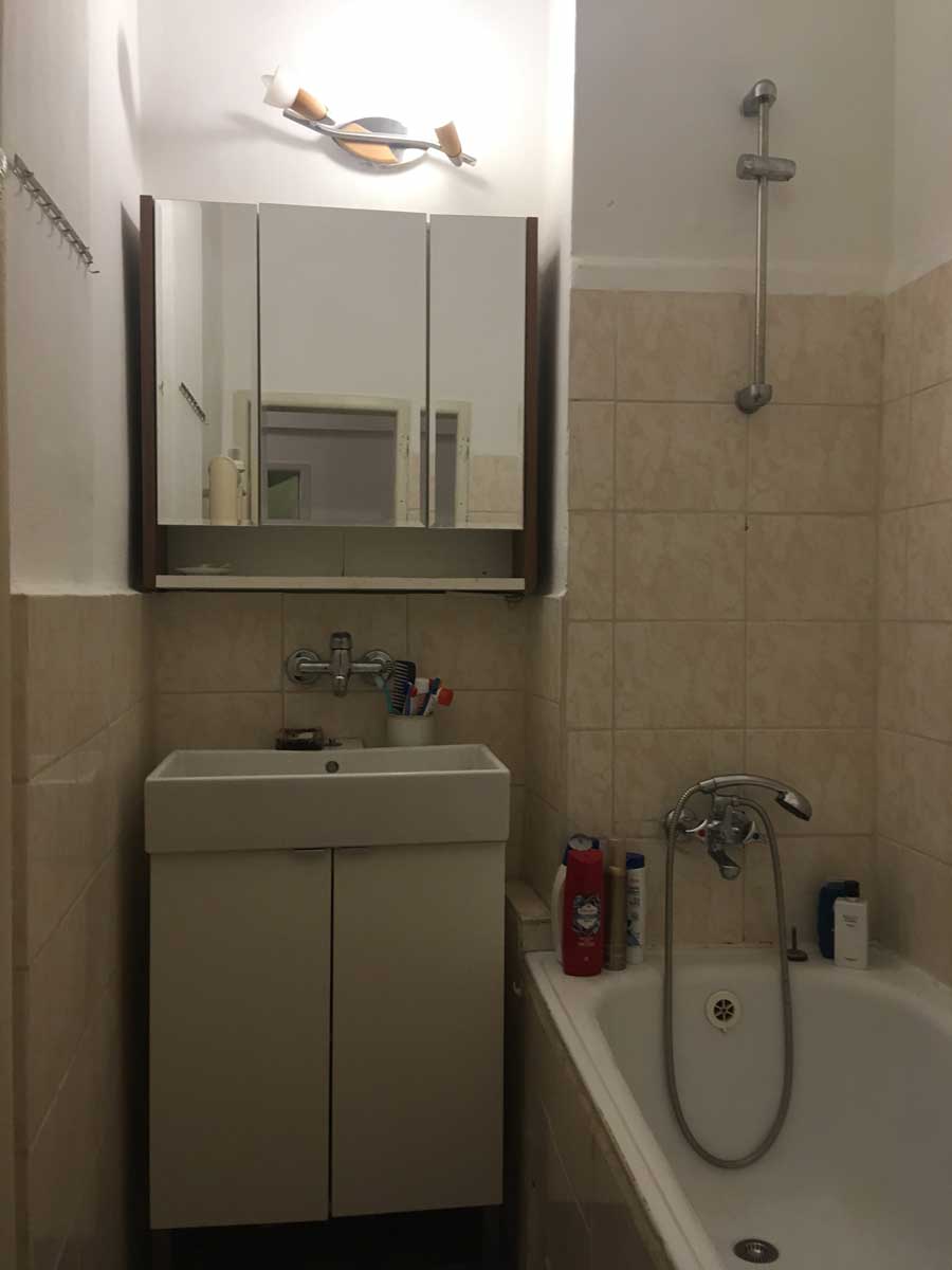 Původní koupelna s vanou a obklady v neutrálních tónech před rekonstrukcí bytu