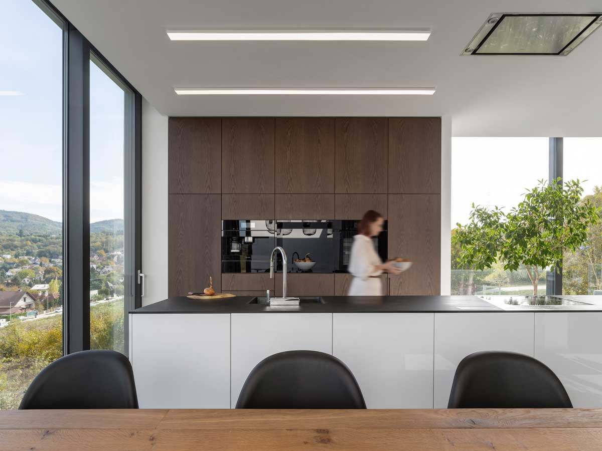 Moderní kuchyň s bílým ostrůvkem, tmavou pracovní deskou a dřevěnou vestavbou.