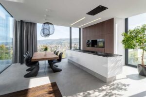 Otevřený obytný prostor s kuchyní a jídelnou, velkoformátová okna a minimalistický nábytek.