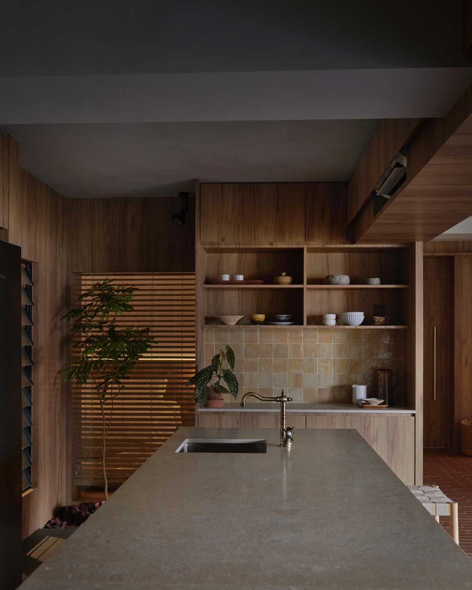 Detail kuchyňského pultu s kamennou deskou a mosaznou baterií ukazuje důraz na přírodní materiály a řemeslné detaily.