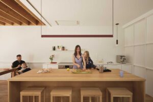 Rodina u velkého kuchyňského ostrůvku z masivního dřeva v otevřeném přízemí domu.