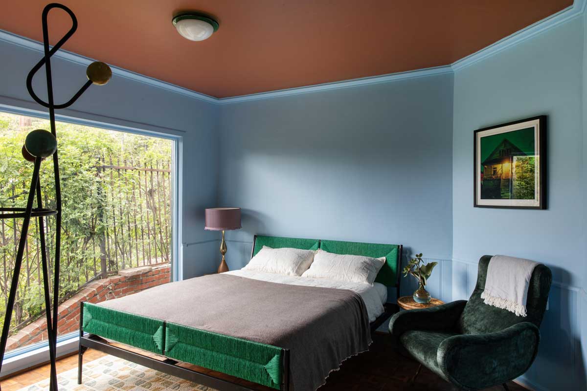 Ložnice s pastelovými tóny, výrazným čelem postele a přirozeným světlem působí klidně a vyváženě.