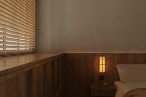 Ložnice s teplým dřevěným obkladem, nízkým nočním stolkem a tlumeným osvětlením navazuje na klidnou atmosféru celého bytu.