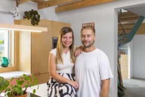 Majitelé nízkoenergetické dřevostavby ve své otevřené kuchyni s přiznanou dřevěnou konstrukcí