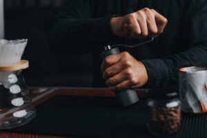 Ruční mlýnek s mlecími kameny při mletí čerstvých kávových zrn