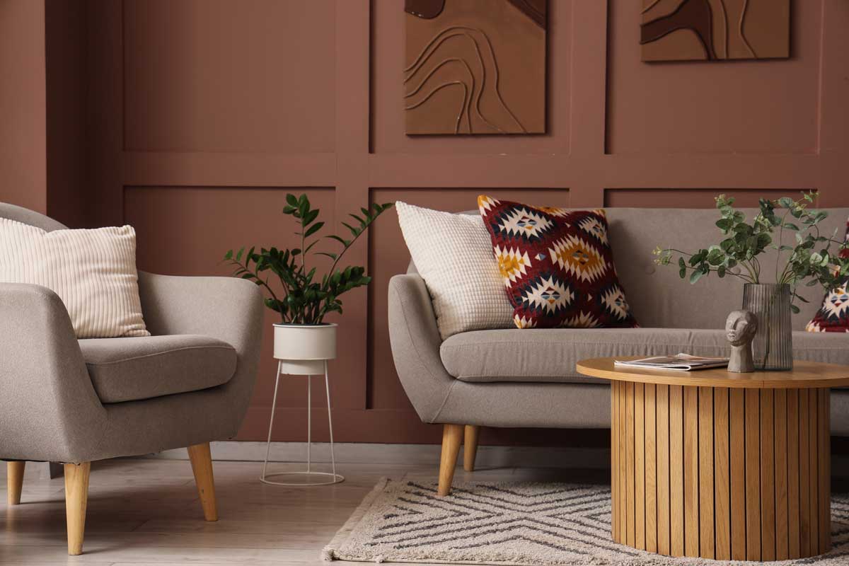 Moderní obývací pokoj kombinuje tlumené barvy s výraznými textiliemi a dřevěnými prvky, které prostoru dodávají hloubku, teplo a osobitý charakter.