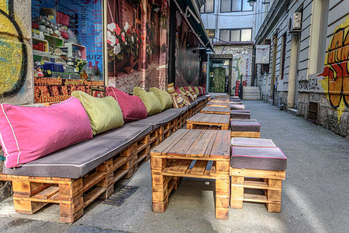 Nábytek z europalet v městské kavárně jako příklad upcyklace v interiéru a veřejném prostoru.