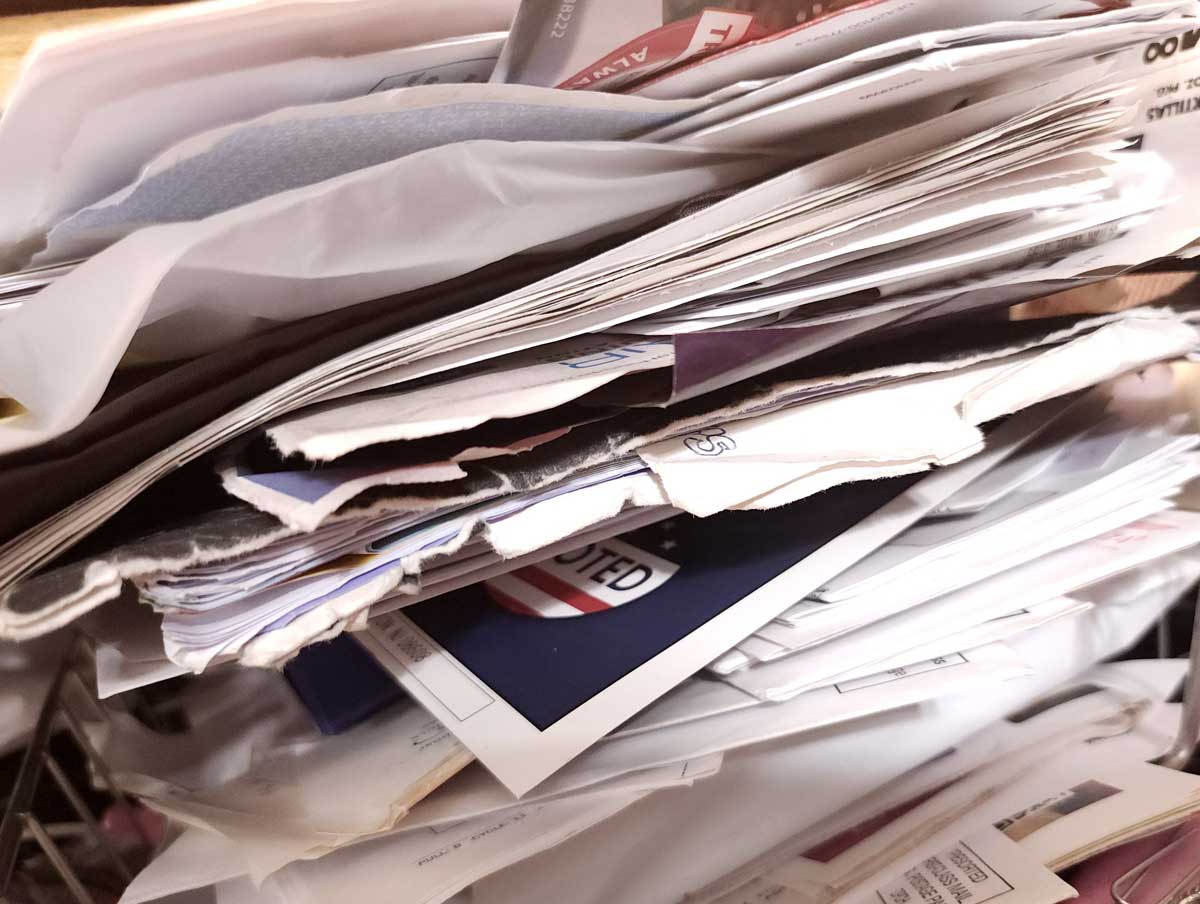 Stoh neuspořádaných dokumentů a papírů představující nahromaděné účtenky a nepotřebné materiály v domácnosti.