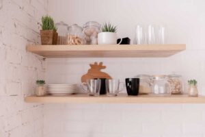 Otevřené dřevěné police s nádobím a dekoracemi vytvářejí lehký a vzdušný dojem loftového interiéru.