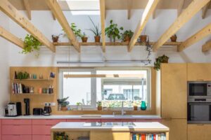 Otevřená kuchyně s ostrůvkem a střešními okny v udržitelné dřevostavbě bez klimatizace