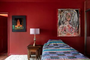 Pokoj pro hosty s výraznou červenou barvou a uměleckými díly nabízí silný vizuální zážitek.