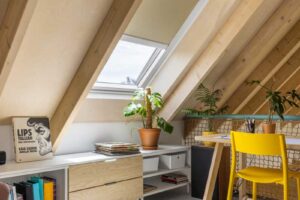 Podkrovní pracovna v nízkoenergetické dřevostavbě s velkým střešním oknem a dřevěným nábytkem
