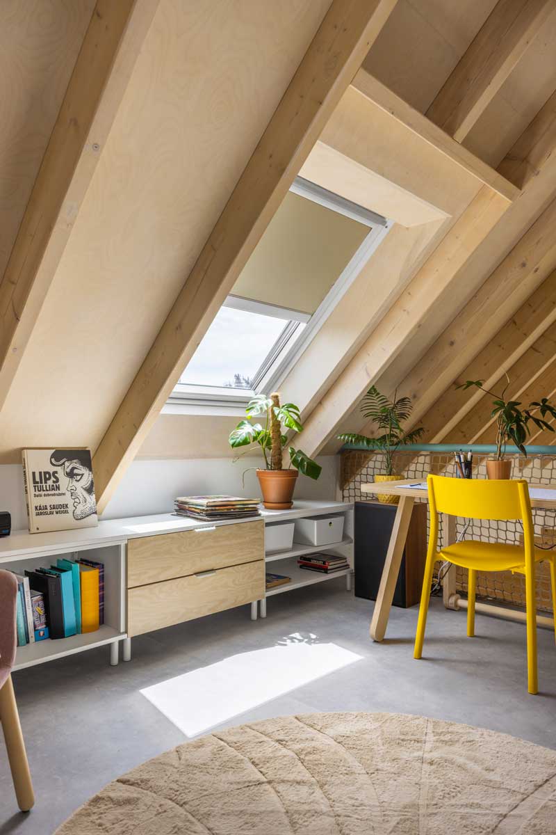 Podkrovní pracovna v nízkoenergetické dřevostavbě s velkým střešním oknem a dřevěným nábytkem