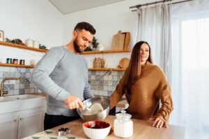 Muž a žena připravují těsto u kuchyňské pracovní desky ve správné ergonomické výšce