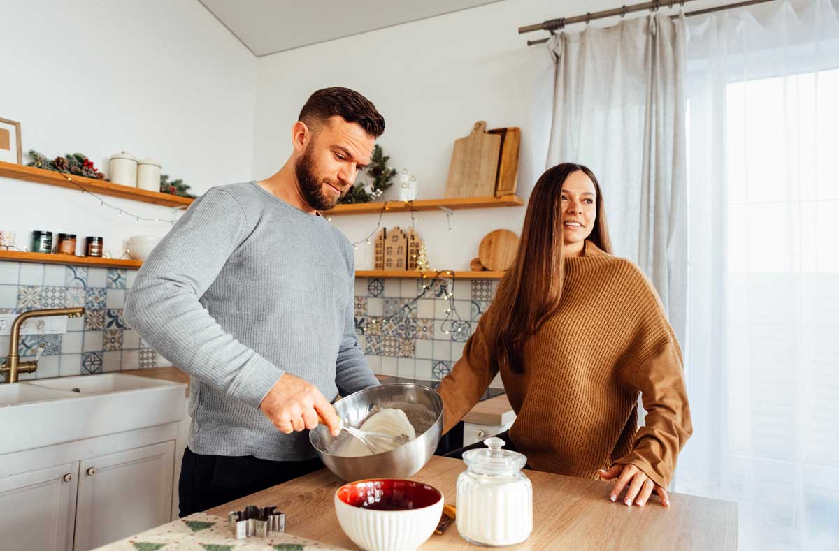 Muž a žena připravují těsto u kuchyňské pracovní desky ve správné ergonomické výšce