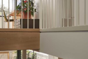 Horní galerie s pracovním koutem, bílým zábradlím a výhledem do obytné části domu.