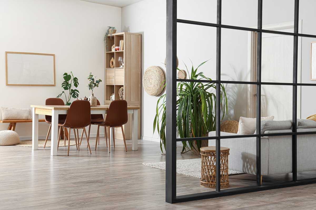 Skleněná příčka s černým rámem odděluje jídelní část od obývacího prostoru bez ztráty světla.
