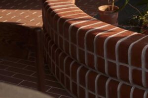 Zakřivená cihlová zídka odděluje jednotlivé části bytu a zároveň slouží jako vizuální i funkční prvek interiéru.