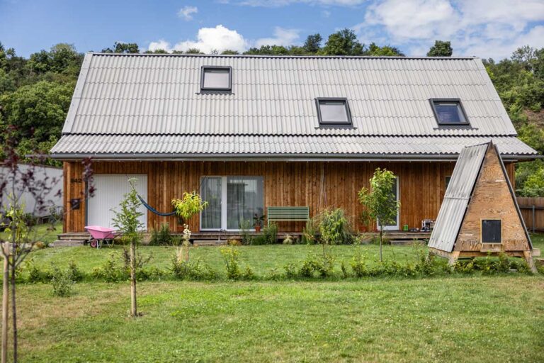 Exteriér nízkoenergetické dřevostavby se sedlovou střechou a zahradním domkem postaveným ze zbylého materiálu