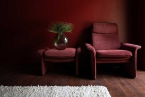 Sametové křeslo v tmavém odstínu vytváří samostatný kout určený k odpočinku a zklidnění.