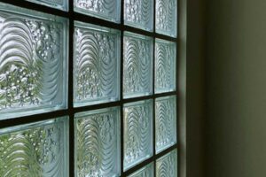 Stěna ze sklobetonu propouští rozptýlené světlo a vytváří strukturovaný filtr mezi interiérem a exteriérem.