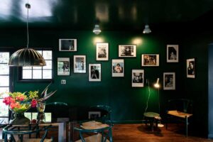 Galerijní stěna s fotografiemi a uměleckými díly propojuje hudební odkaz domu s osobní historií.