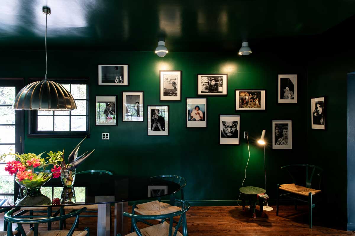 Galerijní stěna s fotografiemi a uměleckými díly propojuje hudební odkaz domu s osobní historií.