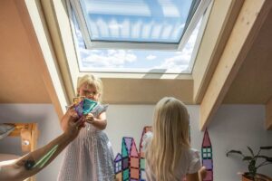 Dětský pokoj se střešním oknem v podkroví nízkoenergetické dřevostavby s přirozeným větráním