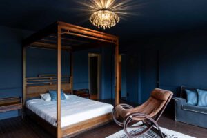 Ložnice s masivní dřevěnou postelí a tmavou barevností propojuje hřejivé materiály s klidnou atmosférou.