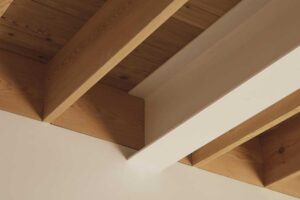 Detail přiznaných dřevěných stropních trámů v kombinaci s bílým stropem.
