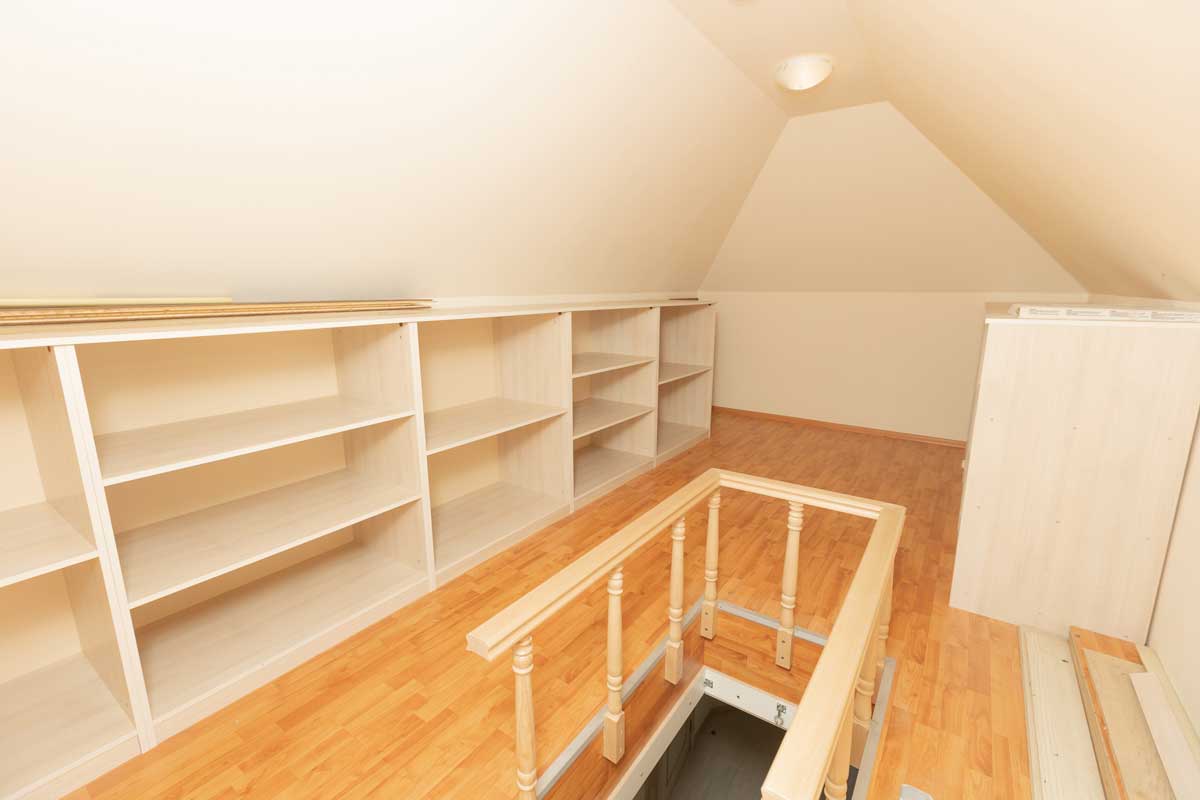 Vestavěné police a nízké úložné systémy podél šikmých stěn efektivně využívají každý centimetr podkrovního prostoru.