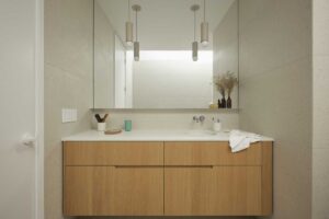 Koupelnová skříňka z masivního dřeva se zapuštěným umyvadlem a velkým zrcadlem přes celou stěnu.