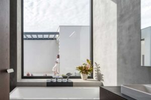 Vana pod velkoformátovým oknem s výhledem do atria rodinného domu.