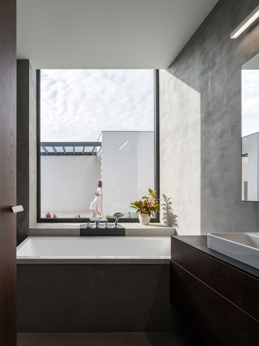 Vana pod velkoformátovým oknem s výhledem do atria rodinného domu.