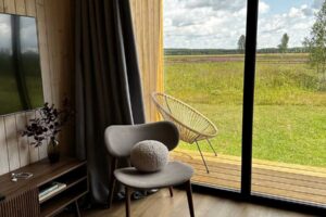 Velkoformátové posuvné zasklení s tmavým rámem stírá hranici mezi interiérem a krajinou a otevírá prostor směrem ven.