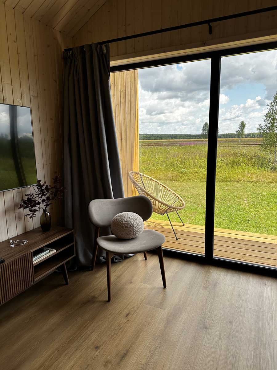 Velkoformátové posuvné zasklení s tmavým rámem stírá hranici mezi interiérem a krajinou a otevírá prostor směrem ven.