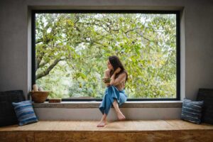 Široké horizontální okno s hlubokým parapetem vytváří klidné místo k sezení a propojuje každodennost s proměnami přírody.