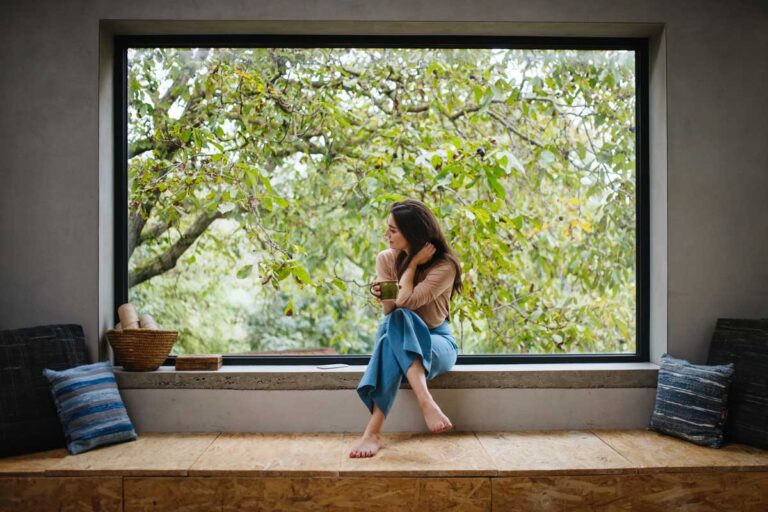 Široké horizontální okno s hlubokým parapetem vytváří klidné místo k sezení a propojuje každodennost s proměnami přírody.