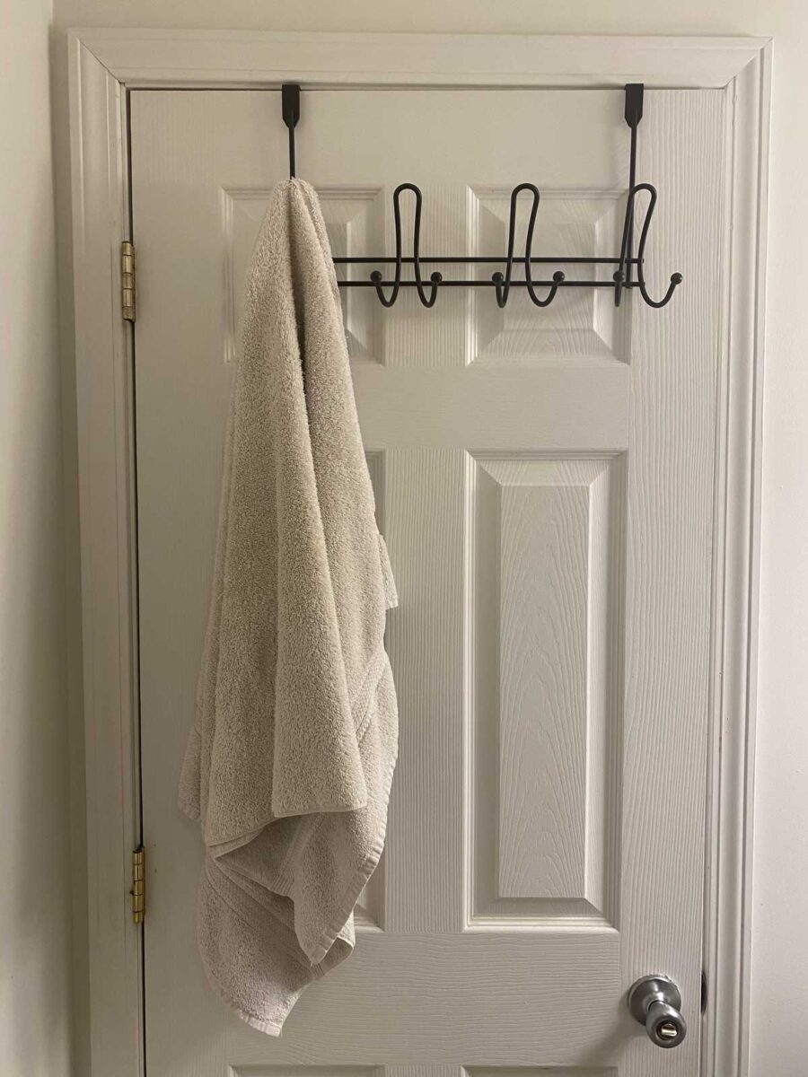 Kovový věšák zavěšený přes horní hranu dveří vytváří úložný prostor bez trvalých zásahů.