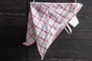 Věšák zavěšený přes dvířka kuchyňské skříňky umožňuje pověsit utěrku bez nutnosti vrtání do zdi.