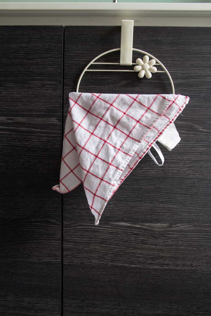 Věšák zavěšený přes dvířka kuchyňské skříňky umožňuje pověsit utěrku bez nutnosti vrtání do zdi.