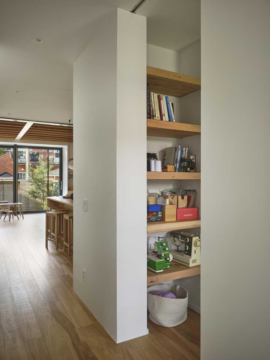 Vestavěné otevřené police z masivního dřeva zapuštěné do niky uprostřed dispozice.