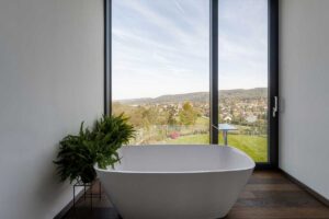 Volně stojící vana u velkoformátového okna s panoramatickým výhledem na krajinu.