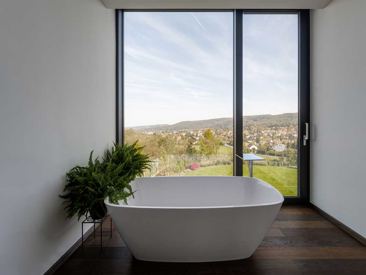 Volně stojící vana u velkoformátového okna s panoramatickým výhledem na krajinu.