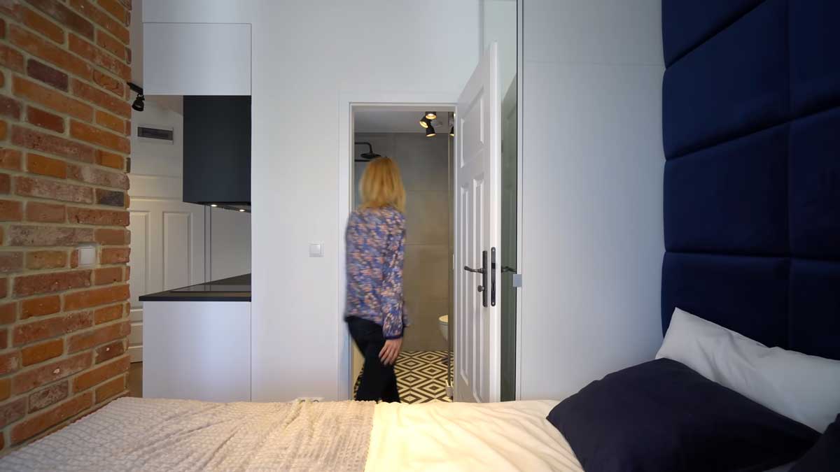 Vstup do malé koupelny v garsonce s posuvnými dveřmi a kompaktním řešením