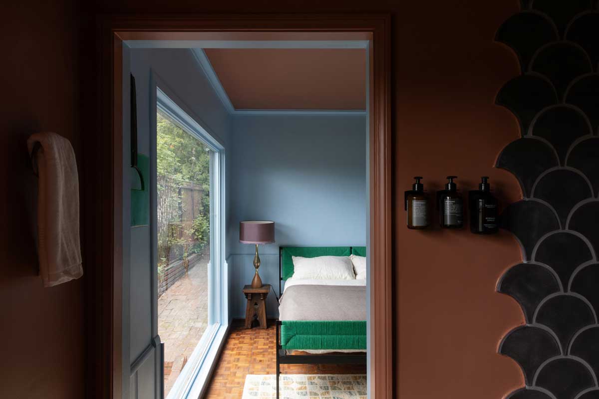 Pohled ze vstupu do ložnice ukazuje plynulé propojení barev, světla a architektury v celém domě.