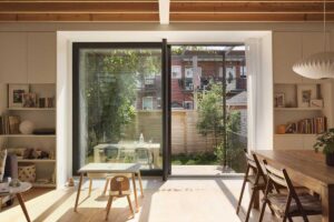 Prosklená stěna propojující interiér s dřevěnou terasou a zahradou ve vnitrobloku.