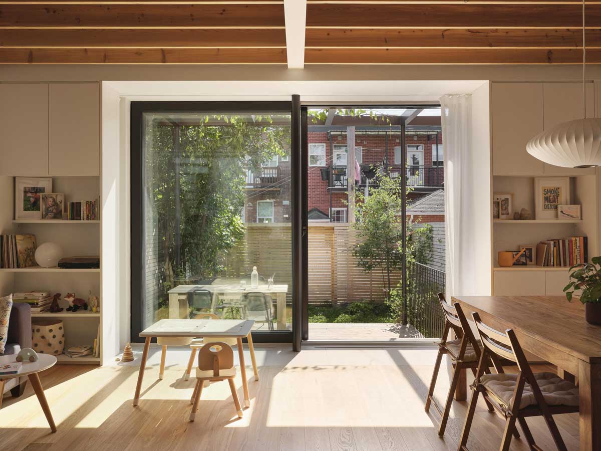 Prosklená stěna propojující interiér s dřevěnou terasou a zahradou ve vnitrobloku.