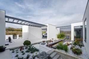 Vstupní zahrada s pergolou, vodním prvkem a výsadbou v bílém kačírku.